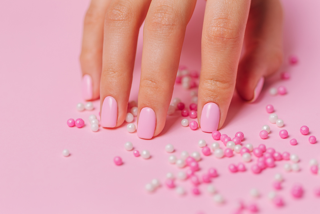 Hand on a Pink Surface with Beads 